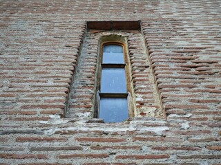 Narrow window illuminating ancient brick wall of historical building