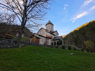 Timotesubani Monastery rising on a green hill in Georgia under the blue sky