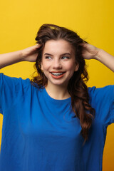Positive teen girl with dental braces in blue t-shirt. Hands behind head, wide smile, looks at...