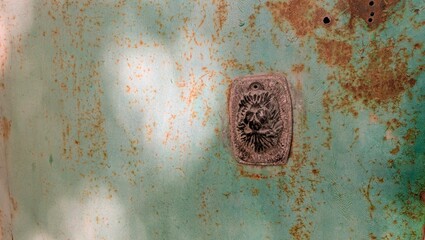 Rusty teal metal surface with intricate emblem in a vintage style
