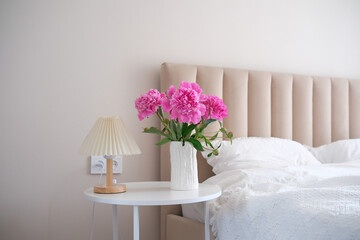 A beautifully styled bedroom featuring an array of soft furnishings and vibrant pink flowers that brighten up the space