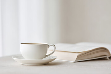 minimalist scene featuring book on table next to cup of coffee