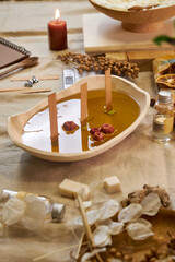 A close-up of freshly poured natural wax in a ceramic bowl with wooden wicks and dried botanicals. The process of creating an eco-friendly handmade aroma candle, combining aesthetics, craftsmanship