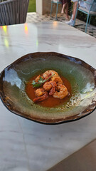 Tasty prawns fried with garlic and spices in tomato sauce close-up in a plate on the table. horizontal