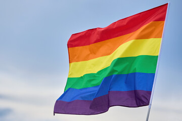 LGBTQ Pride Flag Waving. A vibrant rainbow flag fluttering against a clear sky