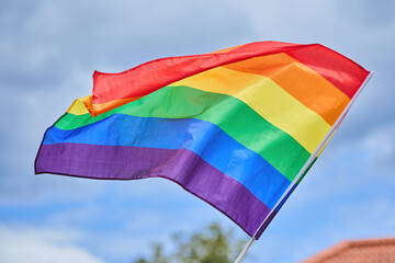 LGBTQ Pride Flag Waving. A vibrant rainbow flag fluttering against a clear sky