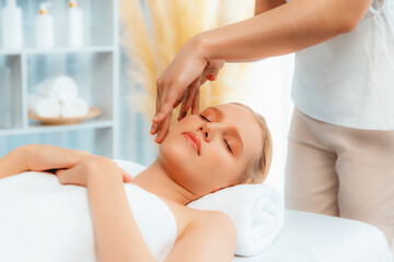 Fototapeta premium Caucasian woman enjoying relaxing anti-stress head massage and pampering facial beauty skin recreation leisure in dayspa modern light ambient at luxury resort or hotel spa salon. Quiescent