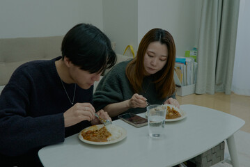 部屋でカレーライスを食べる若い男女
