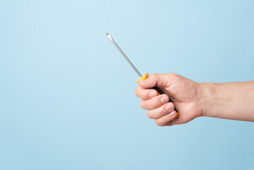 A man's hand holds a screwdriver wrench on blue background with space for design or text