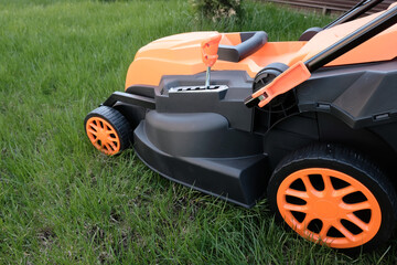 New electric lawn mower against the background of  country house lawn.