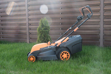 New electric lawn mower against the background of  country house lawn.