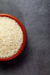 Earthenware bowl full of Basmati Rice on a kitchen countertop in a zenithal photograph
