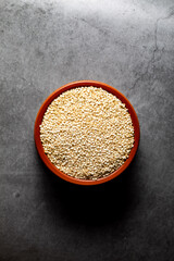 Earthenware bowl full of raw quinoa on a kitchen worktop in an zenithal photograph
