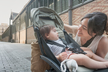 Mother talking to her baby next to stroller on quiet city street