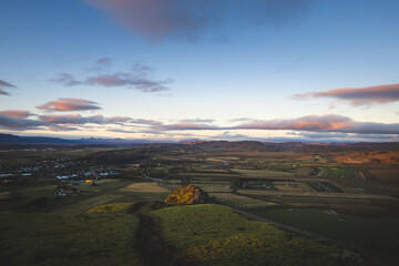 Fototapeta premium Sunset view over the farmlands and rolling hills of Hrunamannahreppur, Iceland, from Midfell. Soft light paints the landscape with warmth and peaceful evening calm