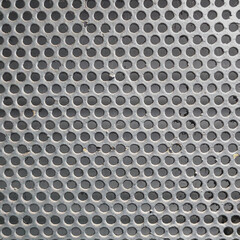Close-up of a gray-painted perforated metal mesh with evenly spaced circular holes. Industrial texture suitable for backgrounds, design elements, or engineering-related themes.