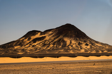 Ash-covered hills in Egypt's Black Desert under a clear sky, scenic and remote landscape. Volcanic