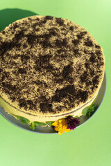 Poppy seed cake decorated with edible flowers on a green table background