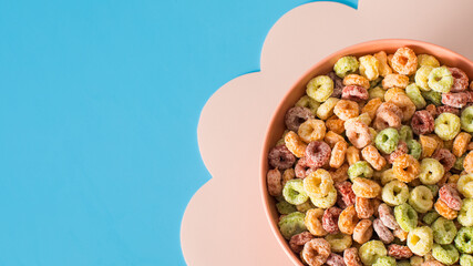 Colorful cereal in bowl on bright blue background for breakfast concept. Copy space