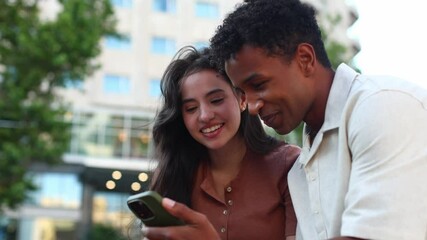 Young couple sharing laughter and connection over smartphone content outdoors - Powered by Adobe