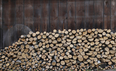 Stacked Firewood against wooden wall. Woodpile of birch firewood in countyside.