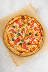 Pizza with tomatoes, olives and mozzarella on wooden board