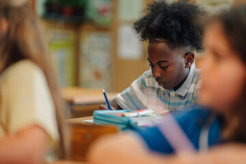 Elementary school student writing in classroom during lesson