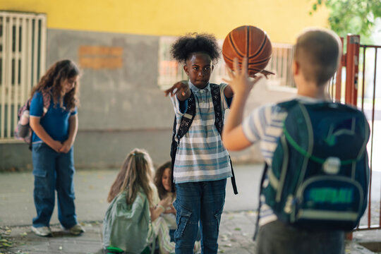 Elementary school students playing basketball outdoors after school