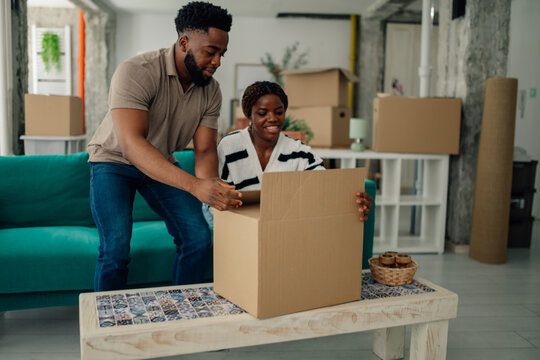 Happy couple unpacking cardboard box in new home