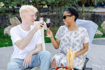 Friends rest together, drink wine, talk to each other on a picnic