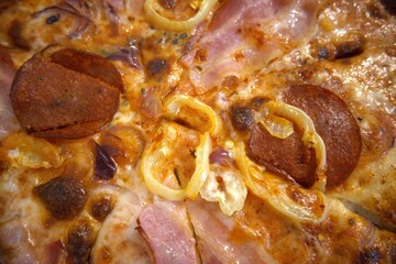 Pizza with ham, salami and hot peppers. in box close up.