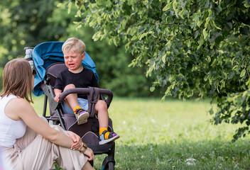 A little boy in a stroller and his mom. Childish hysteria. The child screams, cries, gets cranky...