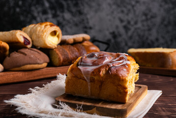 Sweet cinnamon roll on a wooden board on a rustic table