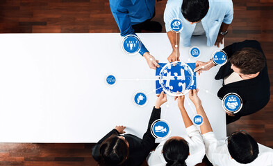 A diverse team collaborates at a modern office table, analyzing puzzle pieces representing various...