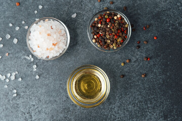 Oil, himalayan salt and pepper on a dark stone background