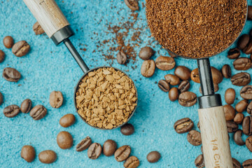 Ground coffee, instant coffee and beans in scoops on blue background