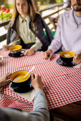Brothers and sister having lunch together on the terrace of a mountain restaurant during a bright spring or autumn day.