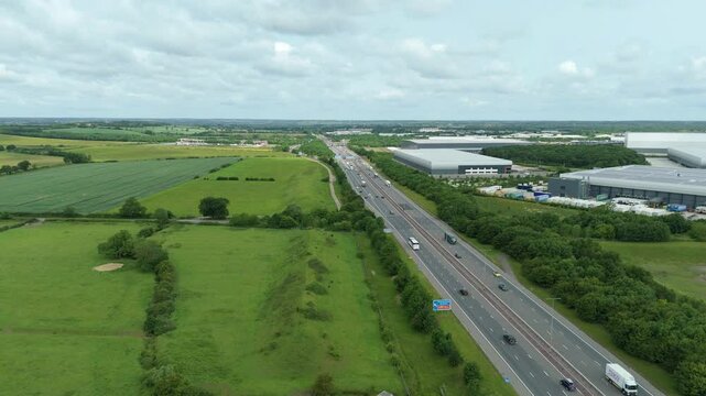 Timelapse hyperlapse aerial drone shot of traffic on motorway highway and  business park warehouse district factory units data centre quantum computing on a sunny day in the UK logistics and transport