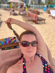 A woman wearing sunglasses poses on the beach in Doha