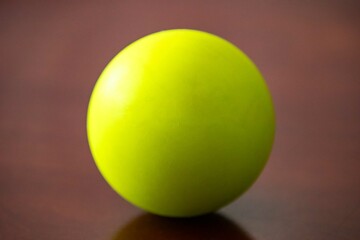A vibrant green sphere resting on a polished wooden surface.