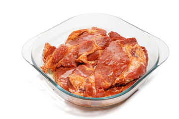 Marinated pork in a transparent glass dish, photographed from the side. The shiny marinade emphasizes the texture of the meat.