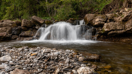 Mountain stream waterfall in Belianske Tatras, Slovakia. Scenic nature with rocks, clear water, forest background. Long exposure landscape perfect for travel and nature themes.