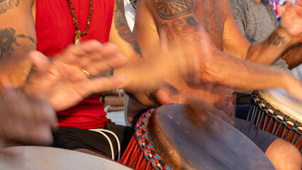 Hands blur in this long exposure of people performing at a drum circle at the beach