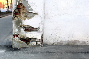A wall with a shabby foundation on the street side.