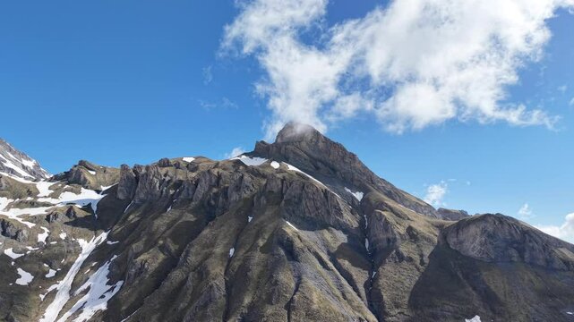 Paysage alpin spectaculaire sous un ciel bleu &eacute;clatant. D&rsquo;imposants sommets rocheux et enneig&eacute;s se dressent au c&oelig;ur des montagnes, offrant une vue majestueuse et sauvage. Vid&eacute;o drone 4k 60fps.

