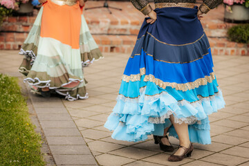 Close-up of dancers in traditional, colorful layered skirts during a lively folk performance,...