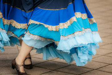 Close-up of dancers in traditional, colorful layered skirts during a lively folk performance,...