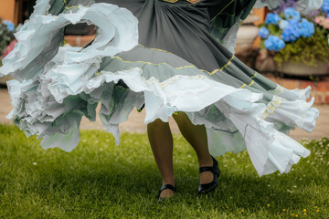 Close-up of swirling layered skirts in motion during a vibrant folk dance, showcasing mint green...