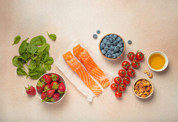 Raw salmon fillets, spinach, strawberries, blueberries, cherry tomatoes, almonds and olive oil. Set of foods that help to reduce inflammation, top view