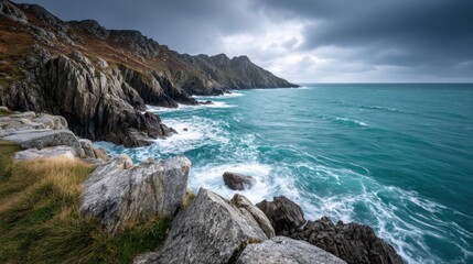Fototapeta premium Strong waves crash against rocky cliffs on a dramatic coastline as dark clouds gather overhead, creating a moody atmosphere during early evening hours.